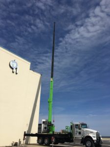 A green and black crane on a truck