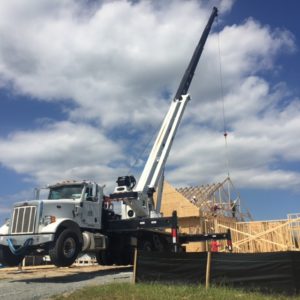Crane holding second frame piece in place for workers