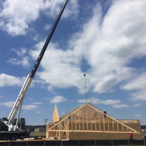 Crane hoisting third piece of framework