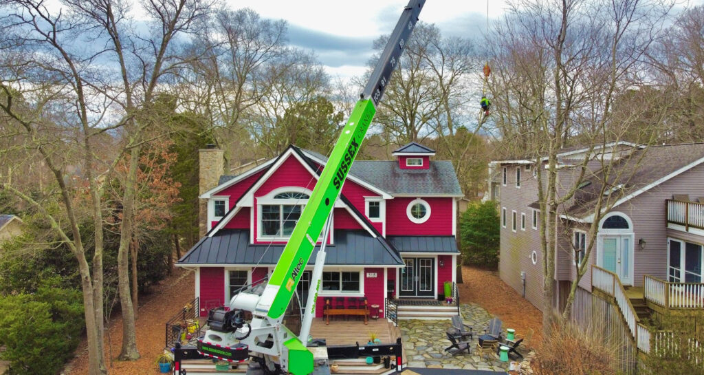 Green Crane doing tree work over a house