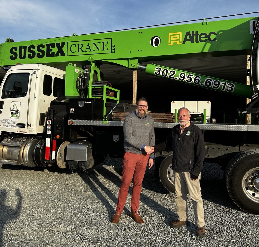 two men standing in front of a green crane